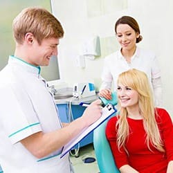 Young woman in dental chair talking to dentist
