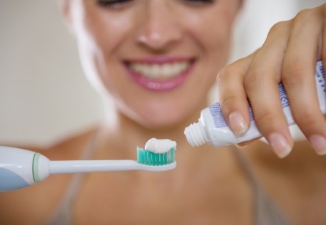 Woman brushing teeth to prevent dental damage