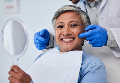 Middle-aged woman smiling with her dental bridge at the dentist’s office