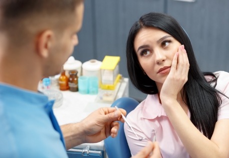 Woman holding cheek during oral cancer risk assessment visit