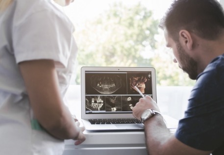 Dentist and patient looking at smile images after oral cancer screening