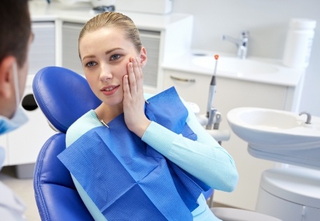 Young woman holding cheek before wisdom tooth extractions