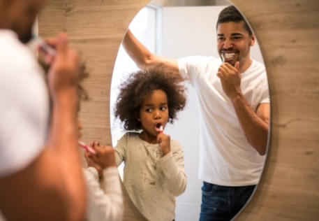 Father and child brushing teeth to maintain healthy smiles