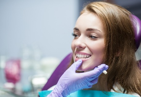 Dentist examining woman's smile after dental crown placement
