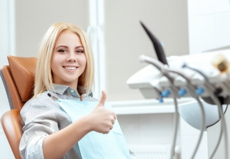 Woman smiling and giving thumbs up during dental appointment
