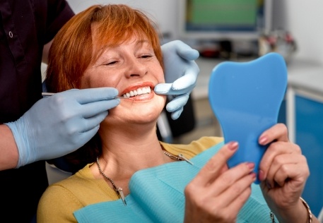 Woman looking at dentures in mirror