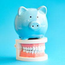 light blue piggy bank sitting on top of a set of full dentures 