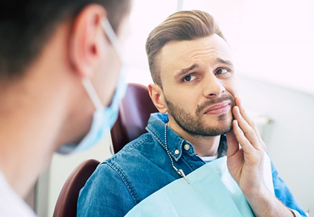 a patient holding his cheek due to a dental emergency