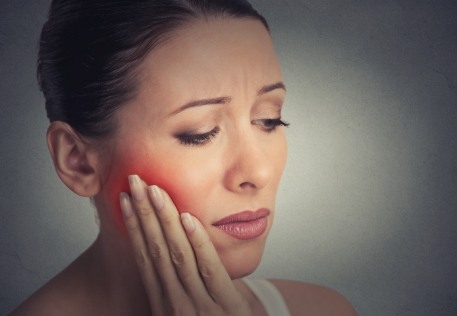 Woman in need of emergency dentistry holding cheek in pain