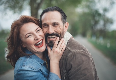 Couple smiling after tooth replacement with dental implants