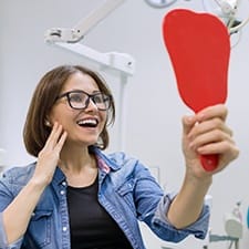 Young woman admiring her new dental implants in Dallas