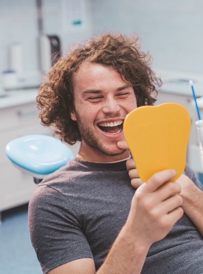 Laughing dental patient seeing his smile in mirror