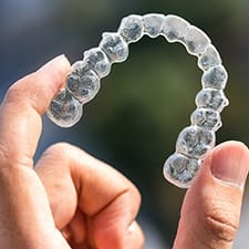 a person holding a set of Invisalign aligners