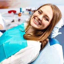 a patient smiling while sitting in a dental treatment chair