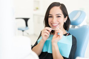 Woman smiling while holding clear aligner