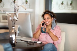 Woman smiling while talking on phone and drinking coffee