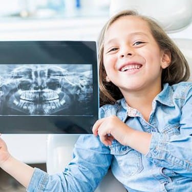 Smiling little girl holding up x-rays