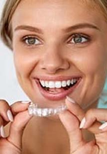 Woman holding up Invisalign tray