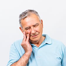 elderly man holding cheek in pain