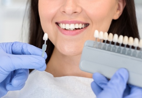 Woman's smile compared to tooth color options before porcelain veneer placement