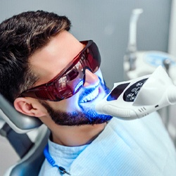 Man smiling while getting in-office teeth whitening in Dallas