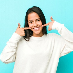 Smiling woman pointing to white teeth