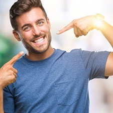 man pointing to his smile after getting teeth whitening in Dallas 