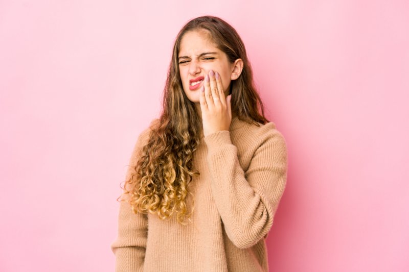 woman holding cheeks due to toothache in Dallas