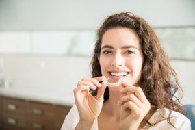 Woman holding her Invisalign aligner during the summer.