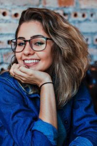 Smiling woman with glasses resting her chin on her hand