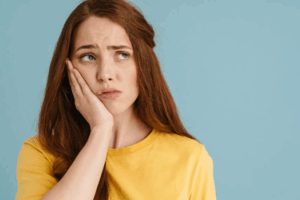Woman holding her aching jaw and looking concerned