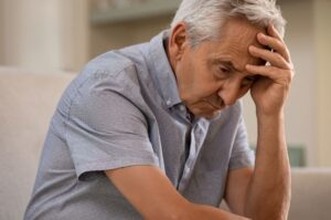 Depressed senior man sitting on sofa 