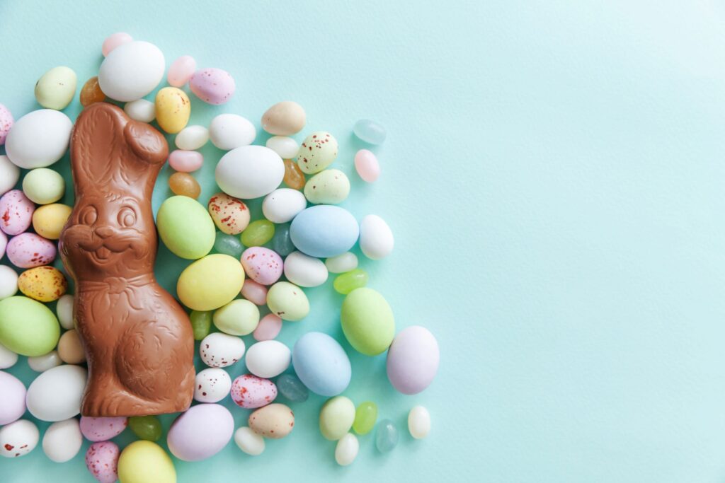 Chocolate bunny and candy eggs on blue surface