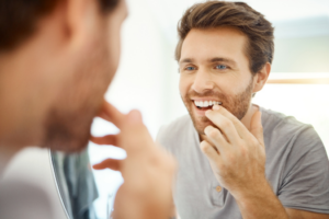 a person smiling and examining their dental crown